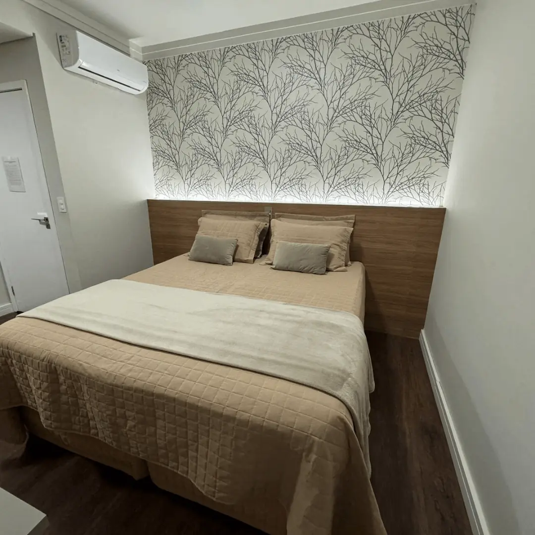 Outro ângulo do Apto Luxo casal, com painel de madeira ripada e TV